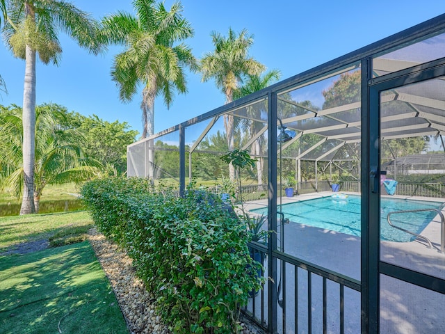 view of swimming pool with glass enclosure and a lawn