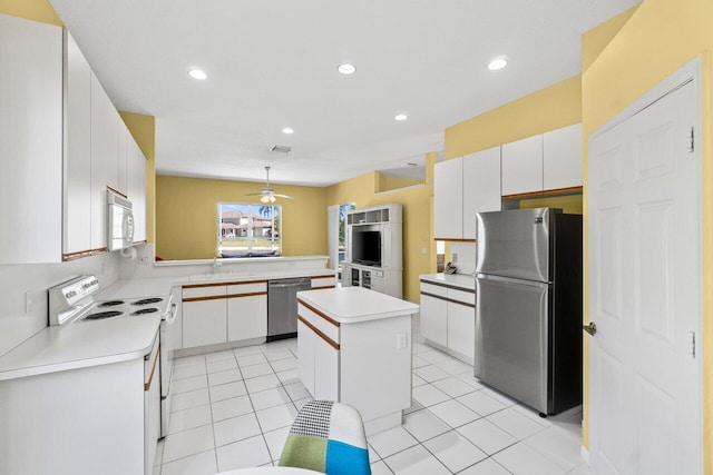 kitchen with stainless steel appliances, a sink, white cabinetry, light countertops, and a center island