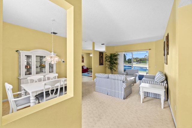 living room featuring a chandelier, visible vents, carpet floors, and baseboards