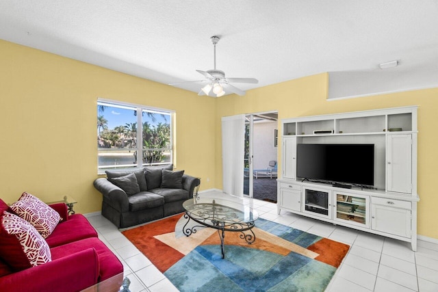 living room featuring ceiling fan, a textured ceiling, baseboards, and light tile patterned floors