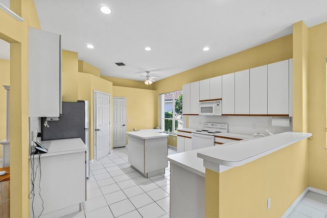 kitchen featuring ceiling fan, a peninsula, white appliances, a kitchen island, and light countertops