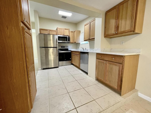 kitchen with stainless steel appliances, sink, and light tile patterned floors