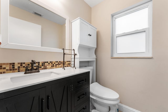 bathroom featuring vanity, backsplash, and toilet