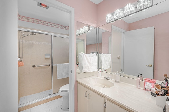 bathroom featuring tile patterned floors, vanity, toilet, and a shower with shower door