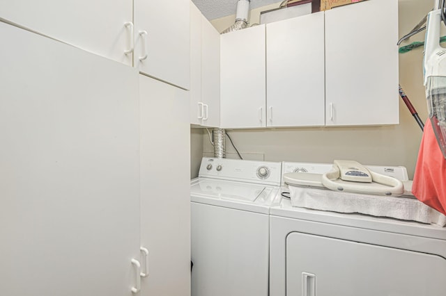 washroom with cabinets, washing machine and dryer, and a textured ceiling