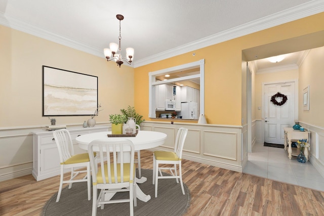 dining area with crown molding, a notable chandelier, and light wood-type flooring