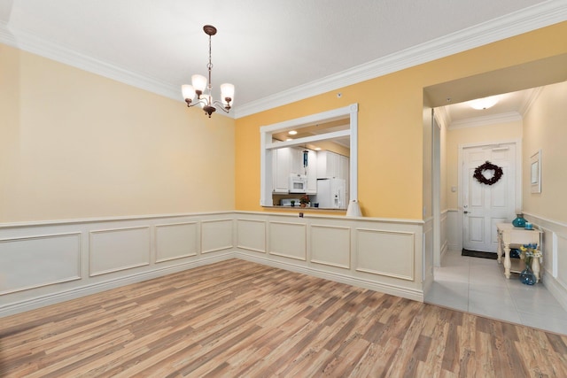 unfurnished dining area featuring a notable chandelier, crown molding, and light hardwood / wood-style flooring