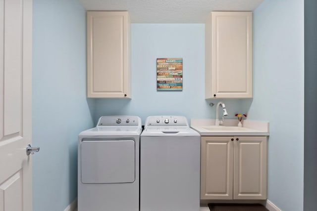 laundry area with cabinets, separate washer and dryer, sink, and a textured ceiling