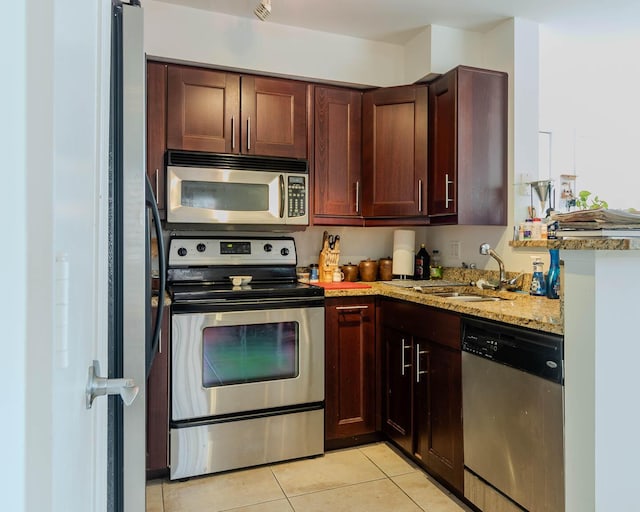 kitchen featuring light stone counters, appliances with stainless steel finishes, sink, and light tile patterned floors