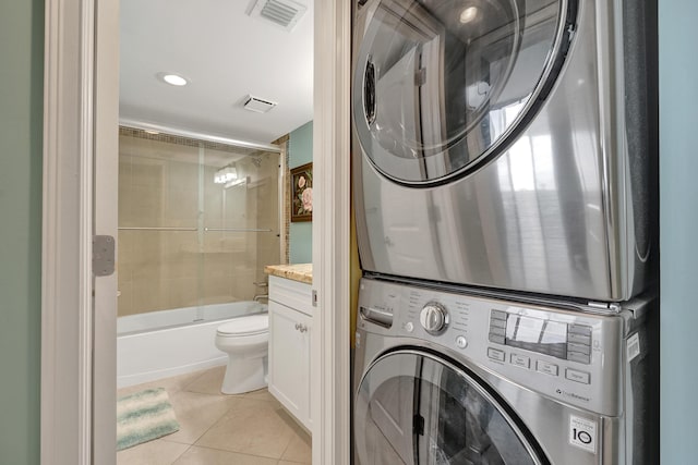 laundry area featuring stacked washing maching and dryer and light tile patterned floors