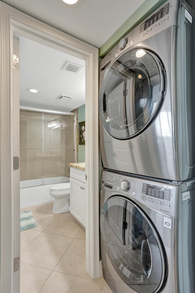 laundry room with stacked washer / dryer and light tile patterned floors