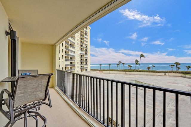 balcony with a water view and a view of the beach