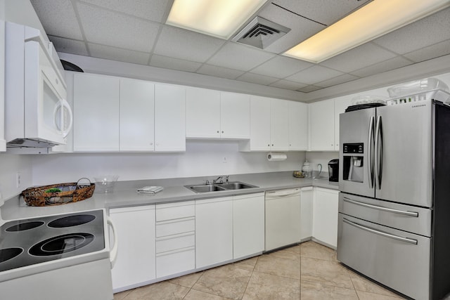 kitchen featuring light tile patterned flooring, a paneled ceiling, sink, white cabinets, and white appliances