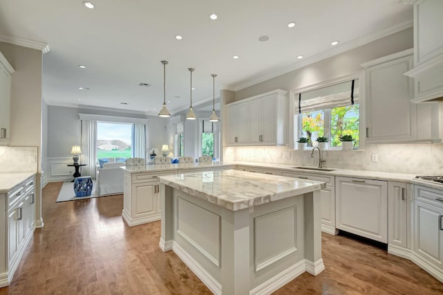 kitchen featuring pendant lighting, white cabinetry, sink, and a kitchen island