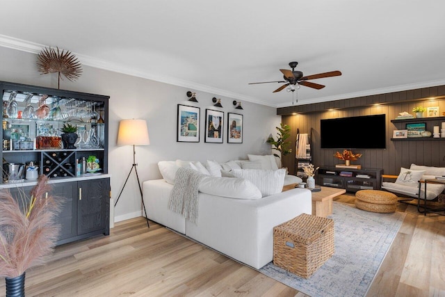 living room featuring hardwood / wood-style flooring, ornamental molding, wooden walls, and ceiling fan