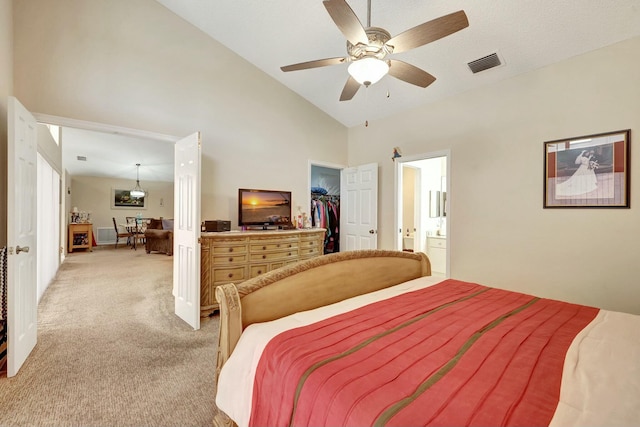 bedroom with ceiling fan, high vaulted ceiling, connected bathroom, light carpet, and a spacious closet