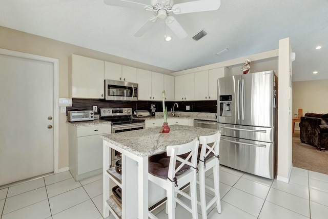 kitchen with light tile patterned floors, stainless steel appliances, a center island, and a breakfast bar