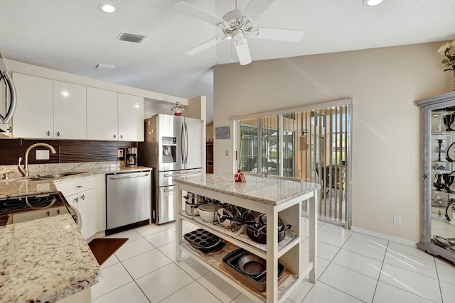 kitchen with white cabinetry, tasteful backsplash, light tile patterned floors, appliances with stainless steel finishes, and a kitchen island