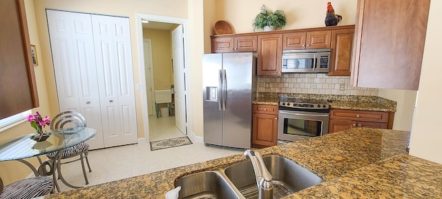 kitchen featuring tasteful backsplash, sink, light tile patterned floors, and appliances with stainless steel finishes