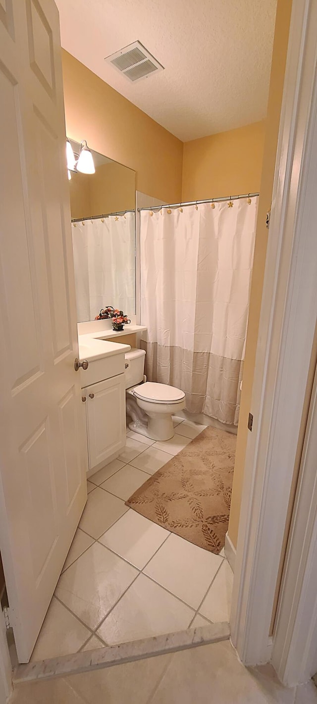 bathroom featuring vanity, tile patterned floors, toilet, and a textured ceiling