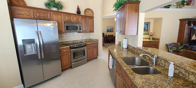 kitchen featuring sink, tasteful backsplash, light tile patterned floors, appliances with stainless steel finishes, and dark stone counters