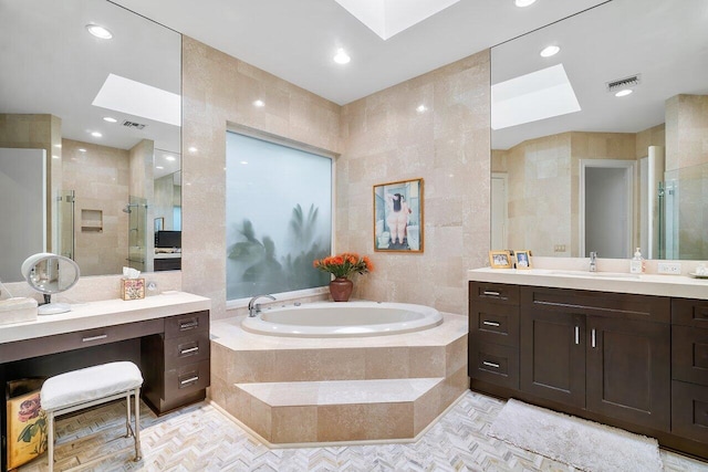 bathroom featuring plus walk in shower, tile walls, vanity, and a skylight