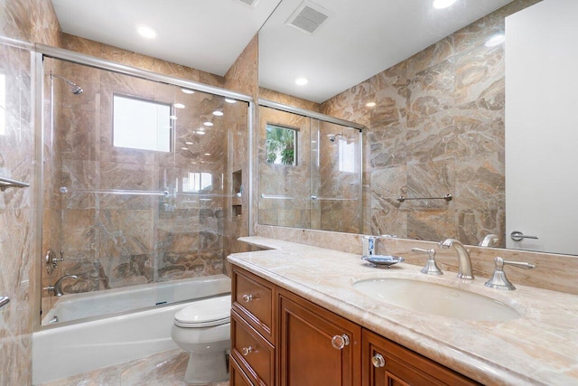 full bathroom featuring vanity, combined bath / shower with glass door, and toilet