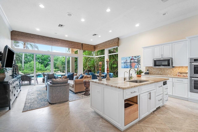 kitchen with white cabinetry, sink, and an island with sink