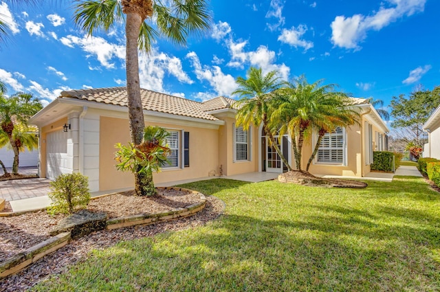 back of house with an attached garage, a yard, a tiled roof, and stucco siding