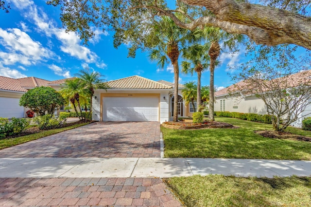 view of front of house with a garage, a tiled roof, decorative driveway, a front yard, and stucco siding