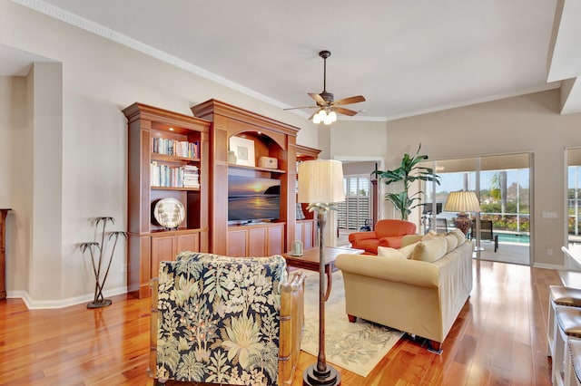 living room featuring baseboards, ceiling fan, light wood-style flooring, and crown molding