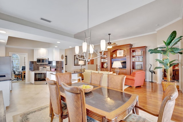 dining room featuring visible vents, light wood-style flooring, ornamental molding, ceiling fan with notable chandelier, and recessed lighting