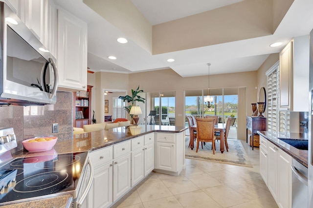 kitchen with decorative light fixtures, white cabinetry, dark stone counters, kitchen peninsula, and stainless steel appliances