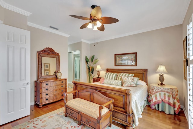 bedroom featuring visible vents, ornamental molding, ceiling fan, wood finished floors, and baseboards