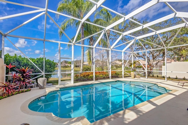 pool featuring glass enclosure, a patio, and a water view