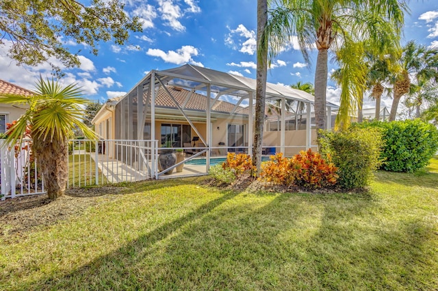 rear view of house with a patio, glass enclosure, and a lawn