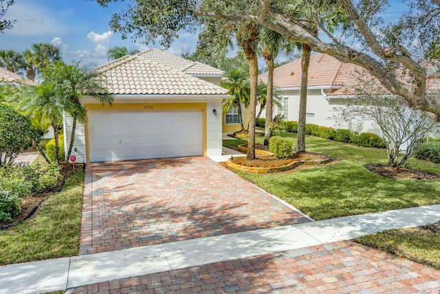 view of front of property featuring a tile roof, an attached garage, decorative driveway, a front lawn, and stucco siding