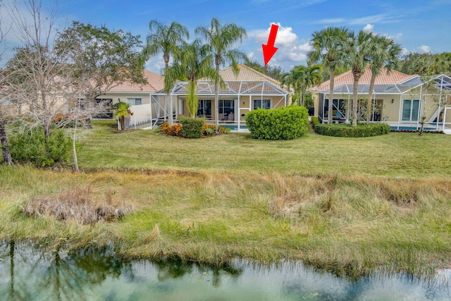 back of house with a water view, a yard, and glass enclosure