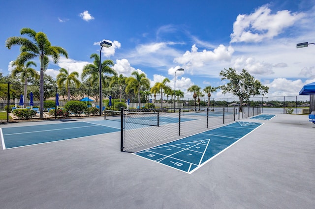 surrounding community featuring a tennis court, shuffleboard, and fence