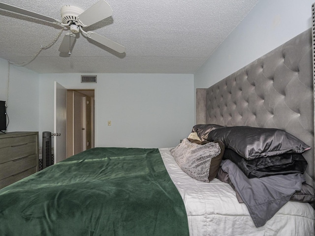 bedroom with ceiling fan and a textured ceiling