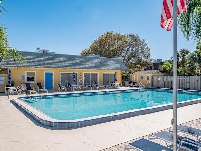 view of swimming pool featuring a shed and a patio area