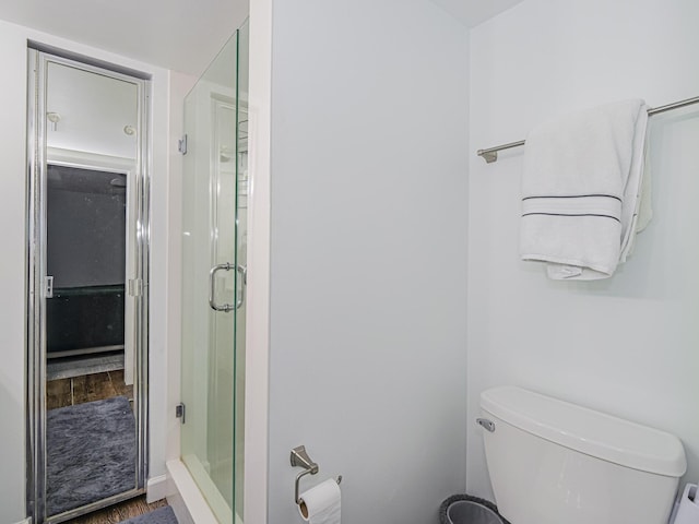 bathroom featuring hardwood / wood-style flooring, toilet, and an enclosed shower