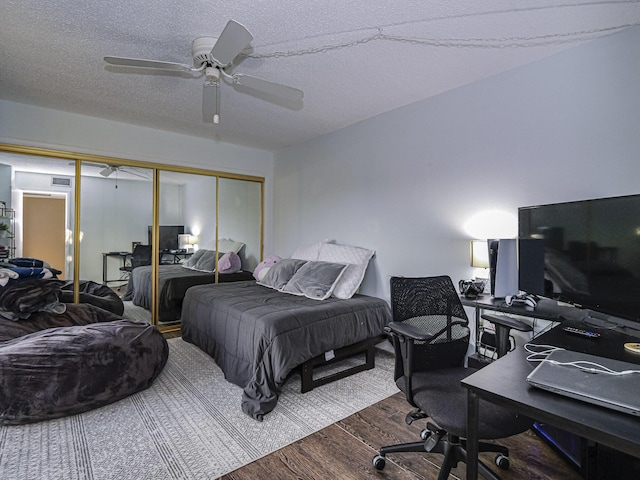 bedroom featuring a textured ceiling, wood-type flooring, a closet, and ceiling fan