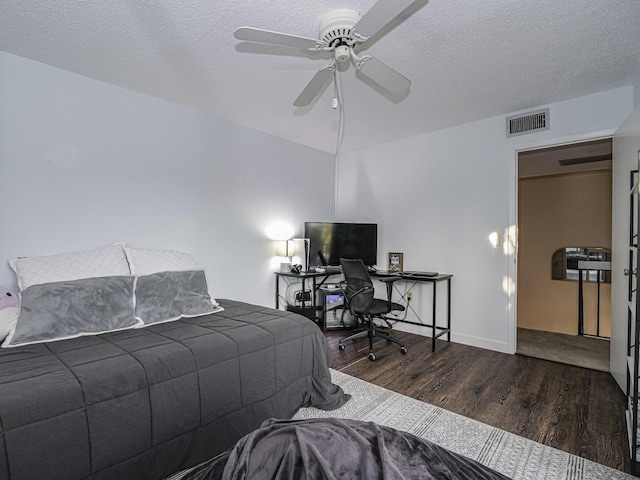 bedroom with dark wood-type flooring, a textured ceiling, and ceiling fan