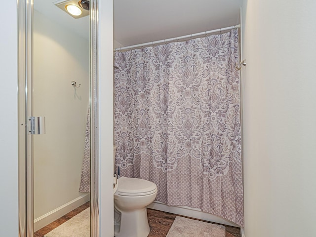 bathroom featuring wood-type flooring, shower / tub combo, and toilet