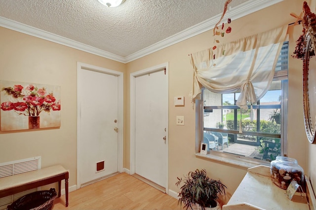 foyer with ornamental molding, a textured ceiling, baseboards, and wood finished floors