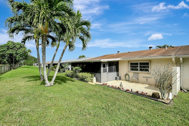 back of property with stucco siding, a lawn, a patio, and a sunroom