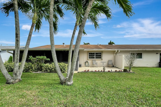 view of front of property featuring stucco siding, a patio, and a front lawn