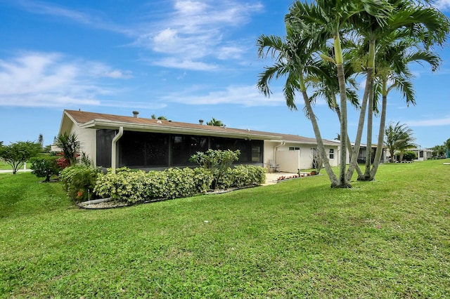 back of property featuring stucco siding, a yard, and a sunroom