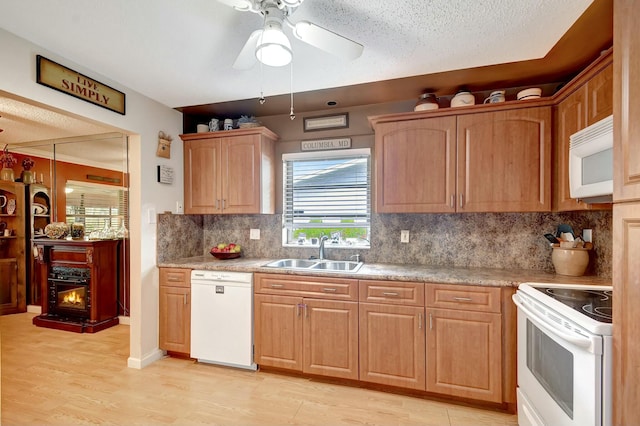 kitchen featuring tasteful backsplash, light countertops, light wood-style floors, white appliances, and a sink